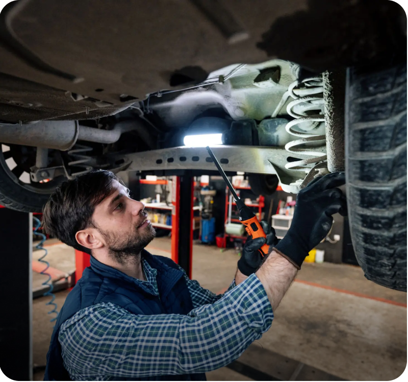 Mechanic inspecting car suspension in garage.