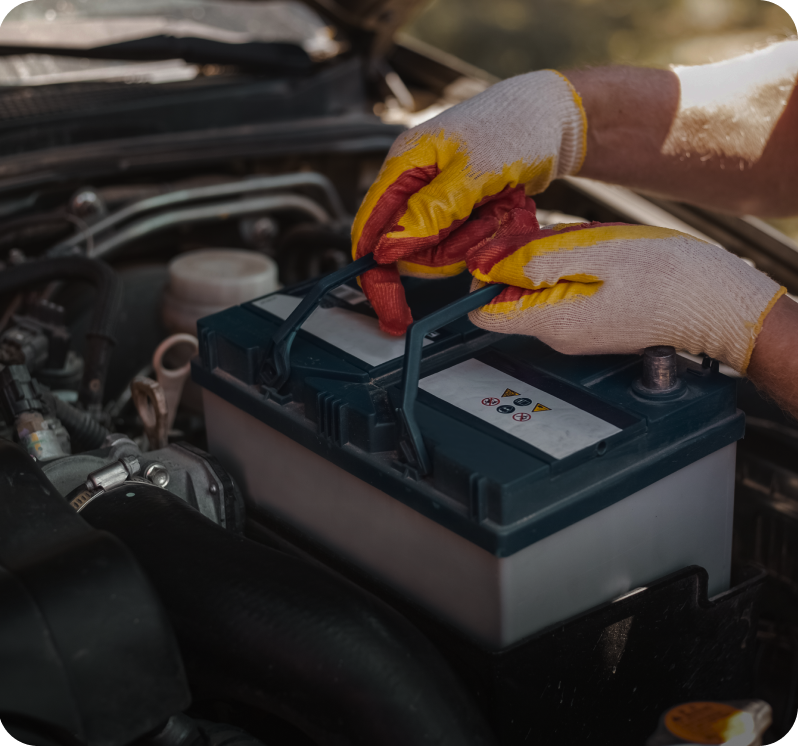Hands with gloves holding car battery.
