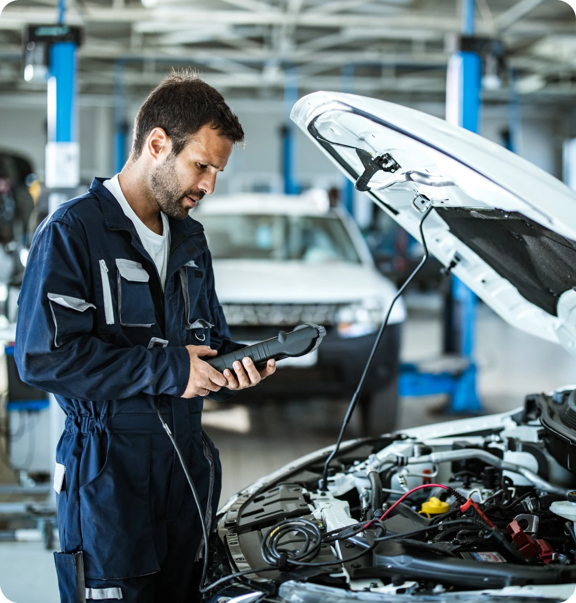 Mechanic diagnosing car engine with scanner